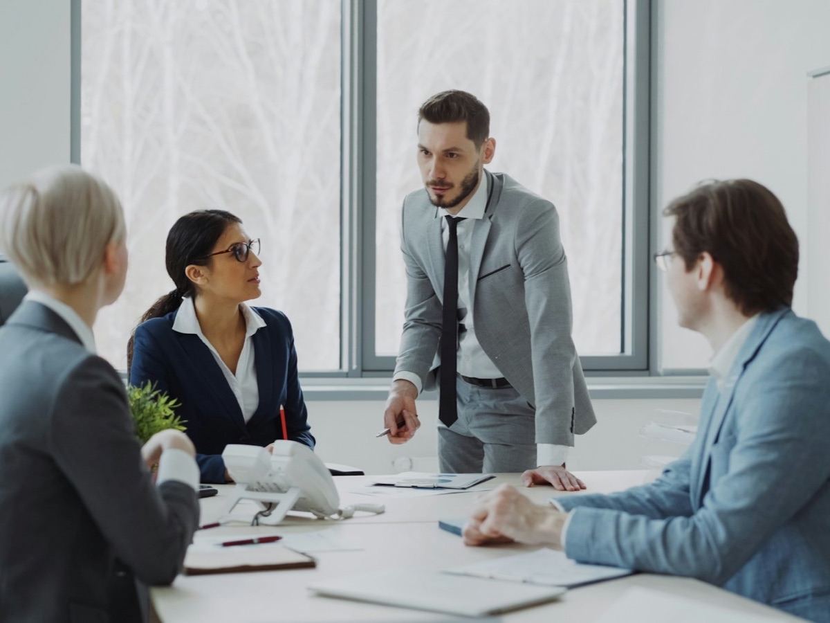 A manager standing to explain a plan to colleagues at a meeting table