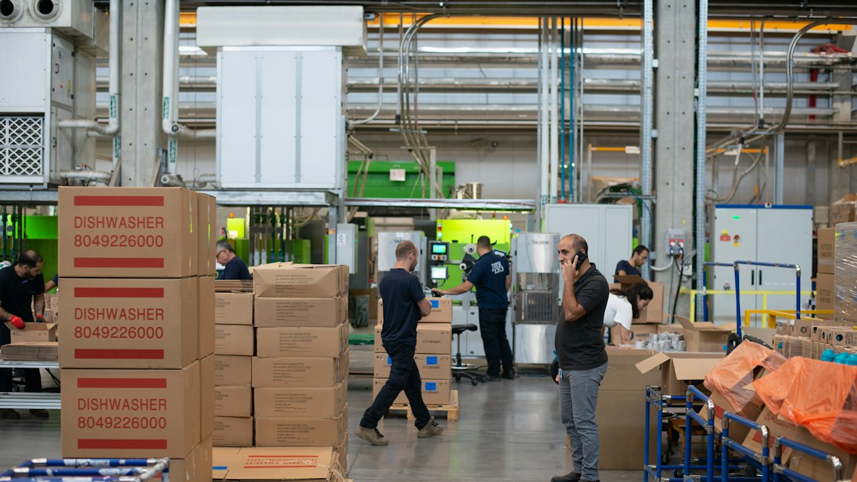 People at work in a large warehouse, among stacks of boxed goods